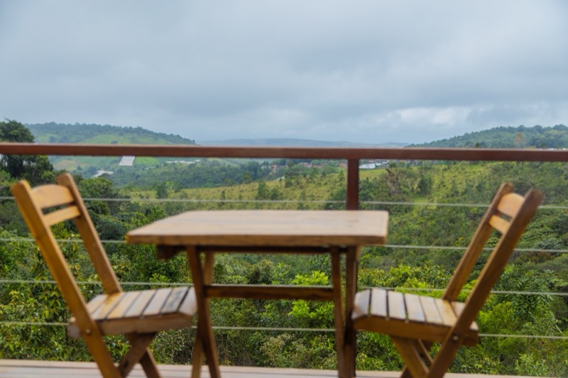 Mesa e cadeiras de madeira no deck, com o vale ao fundo