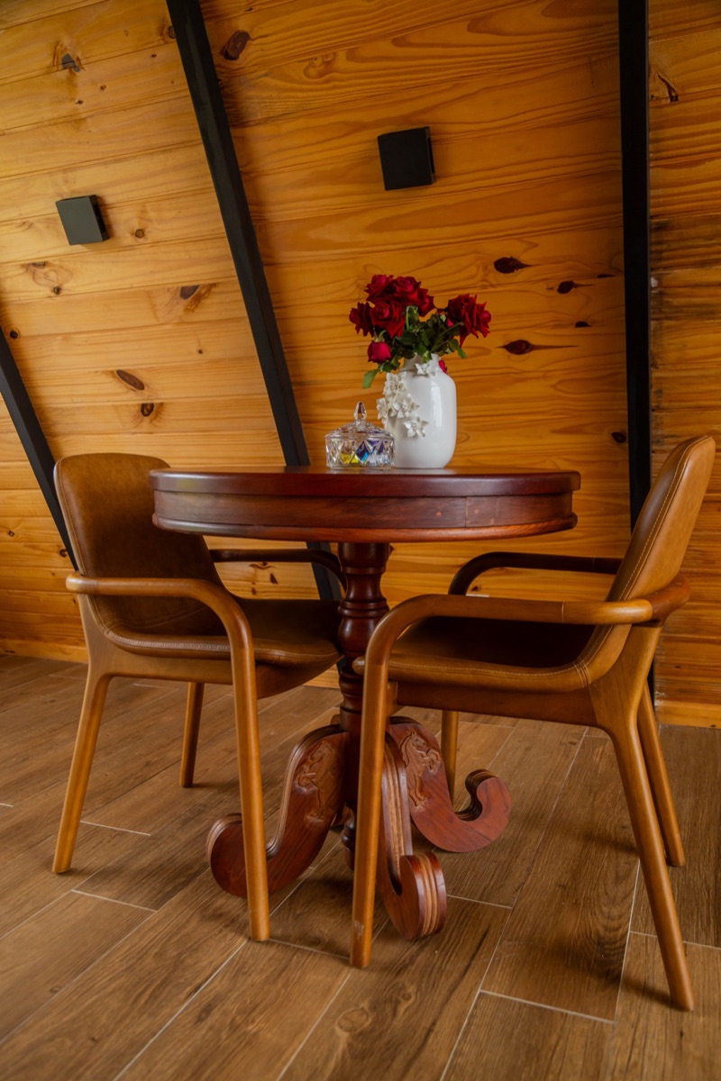 Mesa de madeira com cadeiras de palhinha e um vaso de rosas