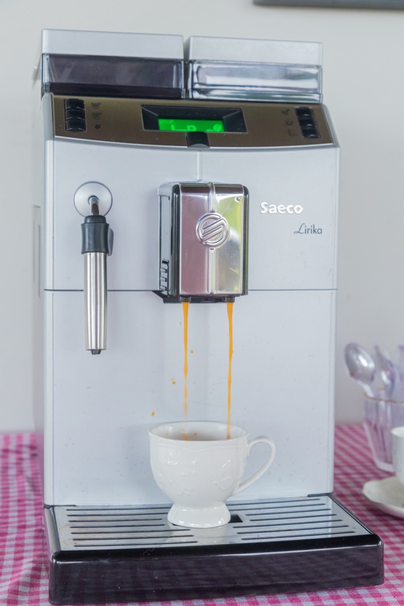 Máquina de café expresso do salão enchendo uma xícara branca, o café à vontade por conta da casa