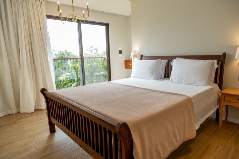 Cama queen ao lado da varanda com vista para o verde
