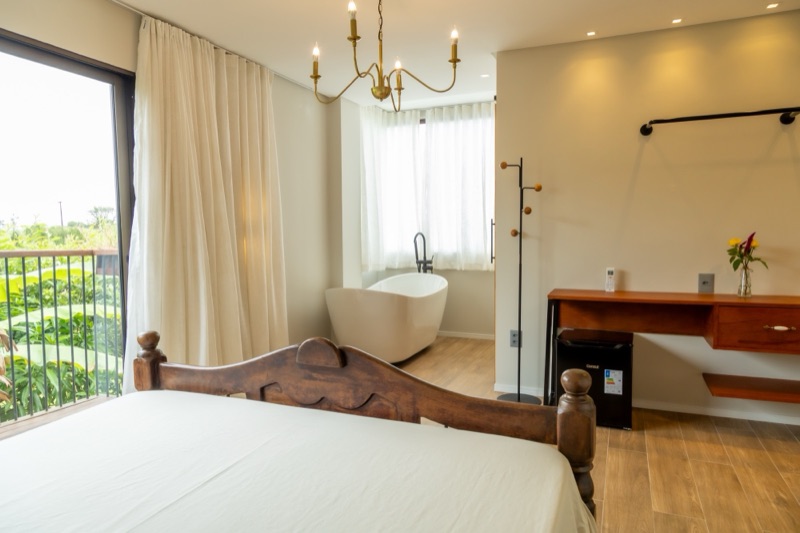 Suíte com lustre dourado, banheira e bancada de madeira