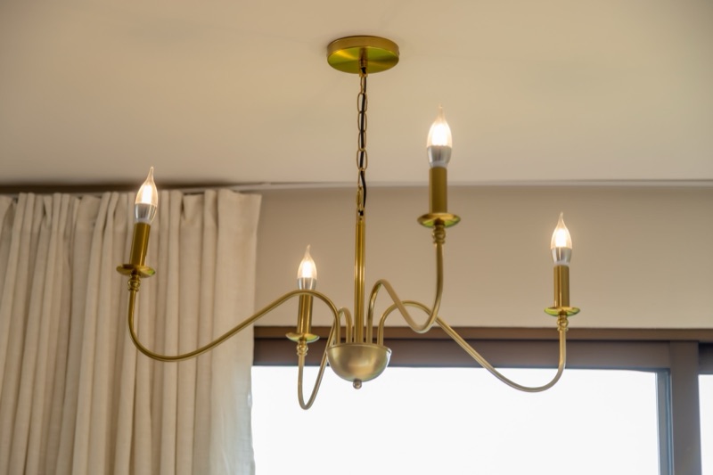 Lustre dourado de velas no teto da suíte